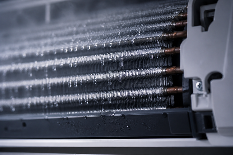 Water droplets forming on AC evaporator coils, explaining why air conditioning units produce condensation during normal operation.